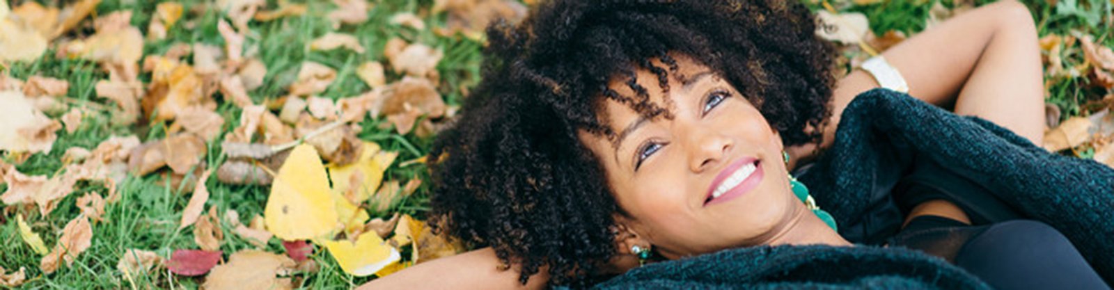 happy woman laying on grass looking at sky.